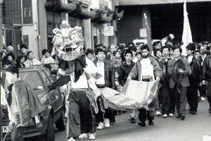 Chinese New Year celebrations in Birmingham in 1990 (Year of the Horse) with a unicorn and flag bearers leading the procession, followed by a small band beating drums-Birmingham Post